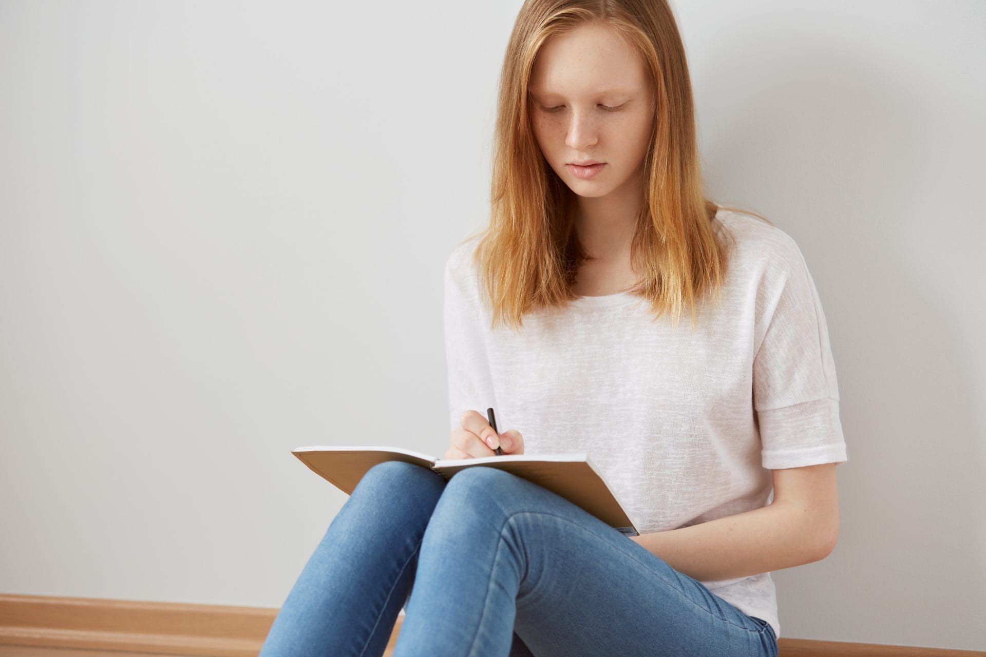 A teenager writing in a notebook, surrounded by colorful stationery, illustrating writing exercises to motivate teens.