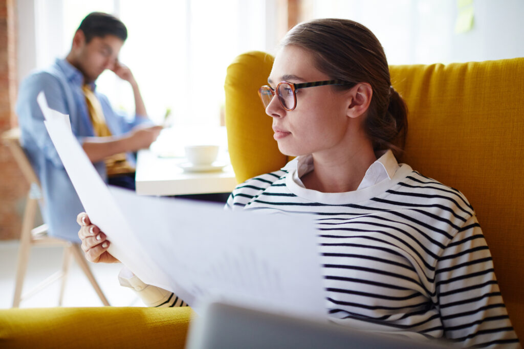Young woman in an armchair reviewing legal documents for teen residential treatment at home.