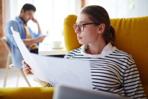 Young woman in an armchair reviewing legal documents for teen residential treatment at home.