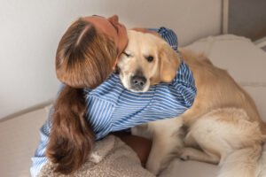 A teenage girl joyfully playing with her pet dog at home, highlighting the bond of emotional support animals for teens.