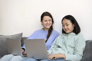 A teenager using a laptop while sitting on a couch, focused on online safety and supporting teens digital habits.