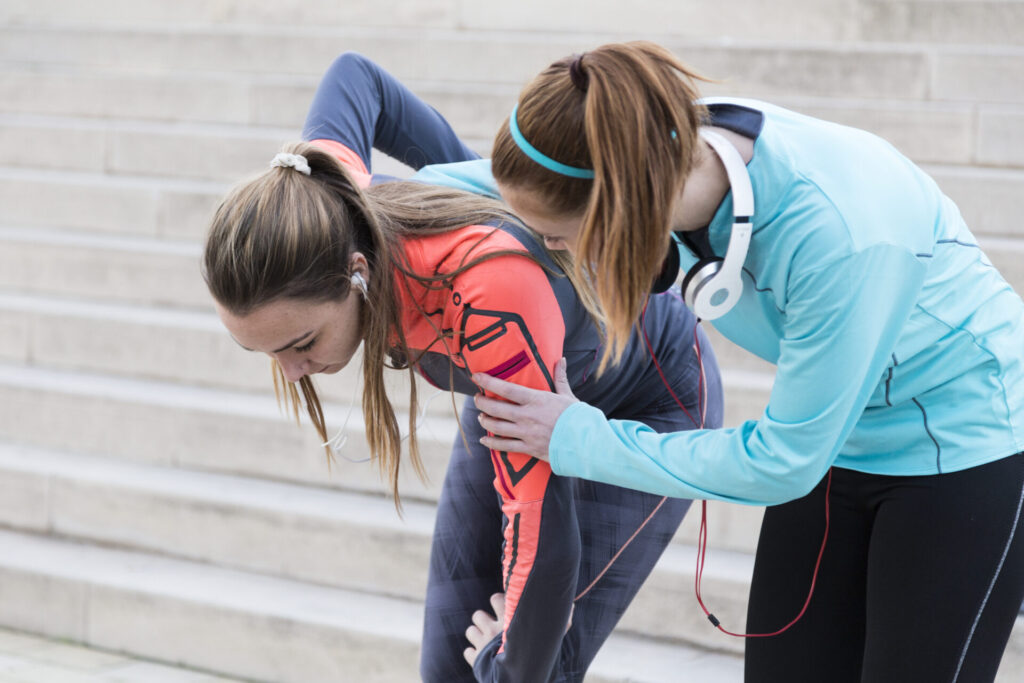 A teenager holding their lower back, showing signs of discomfort, relevant for how to identify chronic pain in teens.