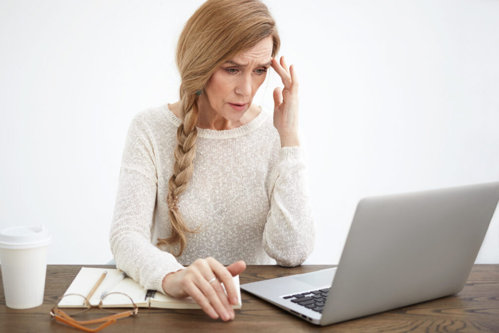 vet therapeutic boarding school reviews - Stressed elderly businesswoman in a white sweater touching her forehead while worki