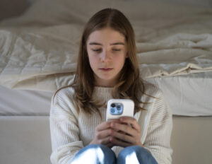 A young girl looking at her phone, reflecting on the Instagram negative impact on teen mental health.