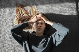 A moody teenager sitting alone in a dimly lit room, reflecting on stressors that make your teen moody.