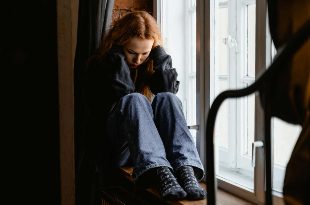 supporting teens with ongoing care - A somber teen sitting alone on a park bench, reflecting on feelings of depression, highl