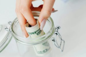 A stack of coins and a piggy bank on a table, illustrating tips on how to save for school tuition.