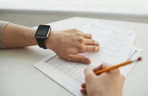 A group of diverse teens studying together, focusing on NHA CCMA practice tests for teens, surrounded by books and laptops.