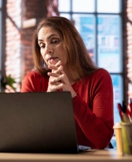 search safely online for teen help programs - A concerned mother using a laptop at home, searching safely online for teen hel