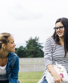 support teen mental health during transitions - Two teenagers sitting on a couch, engaged in a serious conversation, supporti