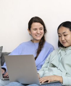 A teenager using a laptop while sitting on a couch, focused on online safety and supporting teens digital habits.