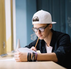 A teen studying at a desk with books and a laptop, showcasing effective study habits for teens in a focused environment.