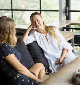 signs your teen needs support during recovery - Two teenage girls sitting together, engaged in a serious conversation, indica