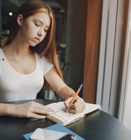 A teenager writing in a journal, reflecting on emotions, highlighting the benefits of journaling for teens.