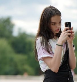 A teenage girl using a smartphone, symbolizing GPS tracking for teen safety and parental peace of mind.
