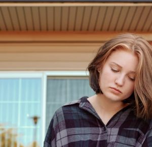 A teenage girl sitting on a bench outdoors, reflecting on emotional resilience strategies for teens while enjoying nature.