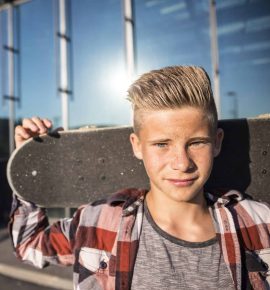 Portrait of teenager holding skateboard