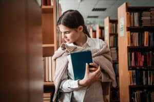 emotional teen girl in the library. Education at school or university. A stack of books