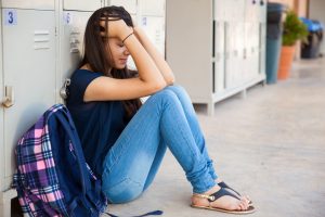 help teens with stress related absences - A stressed teen sitting at a desk with a laptop, looking overwhelmed by schoolwork,