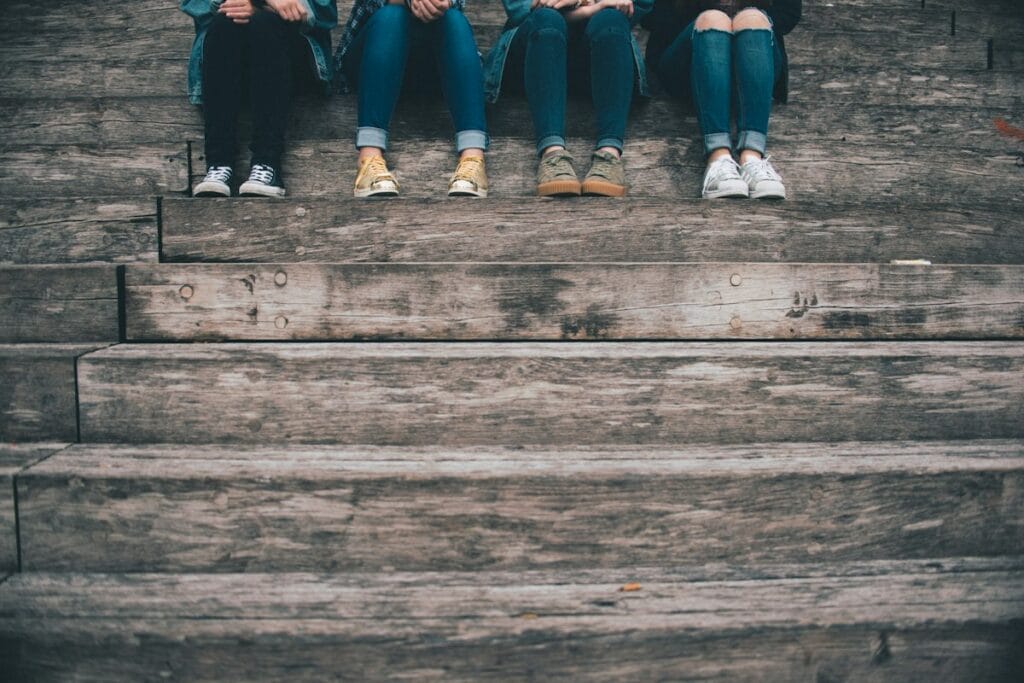 How to Help Your Teen Handle Peer Pressure 2 Group of teens sitting together on wooden stairs, facing peer pressure